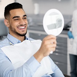 a patient checking his new veneers with a mirror