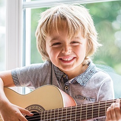 Smiling little boy playin guitar