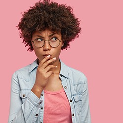 Woman with questions for her Lisle cosmetic dentist on pink background 