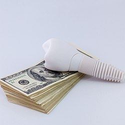 cost of dental implants in Lisle demonstrated by money and a model implant