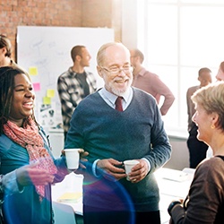 Diverse group of people holding cups and talking in front of a whiteboard