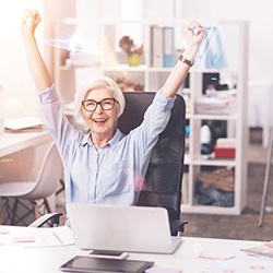 Woman at work smiling and holding hands up triumphantly