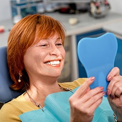 Red-haired female dental patient checking smile in mirror