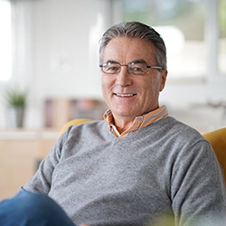 Man in grey shirt sitting in chair and smiling
