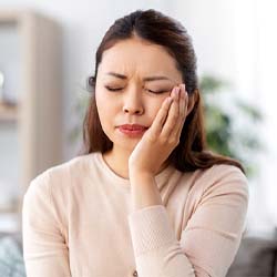 Woman with a toothache in Lisle holding her cheek