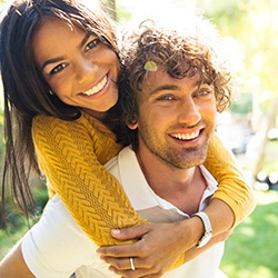 Woman hugging man in white shirt from behind