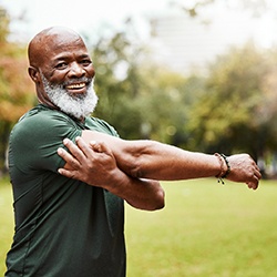 Senior man smiling and doing stretches outside