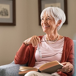 Senior woman smiling and reading at home