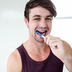 Man brushing his teeth with a blue toothbrush