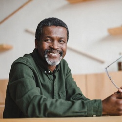 man sitting at table and holding his glasses in his hands