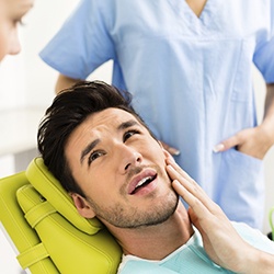 Man in dental chair holding jaw