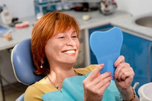 Senior woman checking smile after treatment for gingivitis