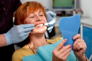 An older woman examining her teeth.