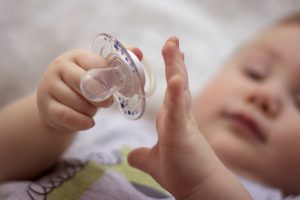 baby playing with clear pacifier