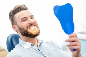 Man at dentist in Lisle looking in mirror.