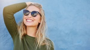 woman in sunglasses enjoying the results of her teeth whitening in summer 