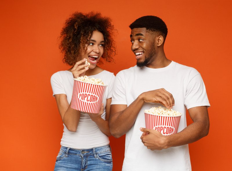 man and woman eating popcorn