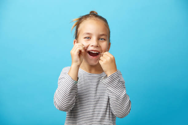 child flossing their teeth in the bathroom mirror