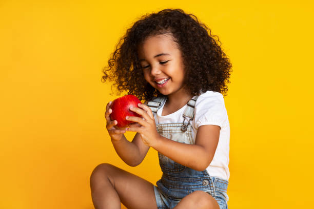 child holding apples and smiling