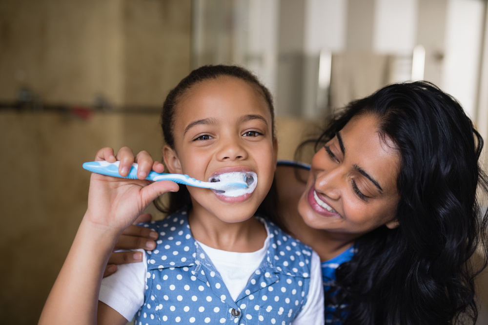 parent helping child brush teeth