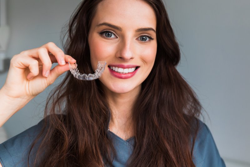 Young woman holding her Invisalign aligner