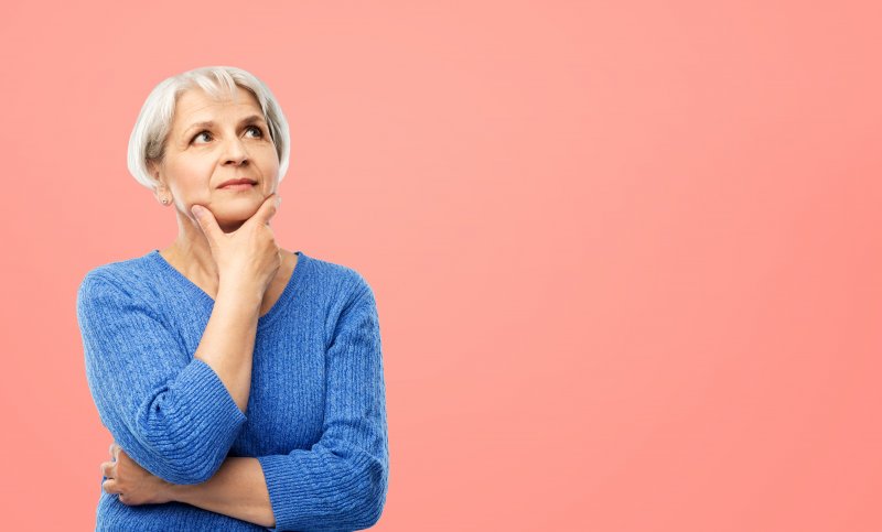 Woman holds chin with questioning expression.