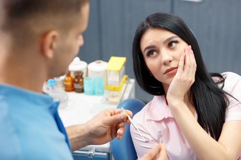 Patient holding their cheek due to tooth pain